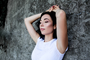 portrait of young pretty woman posing against the sreet grey wall/ Lady wearing white dress