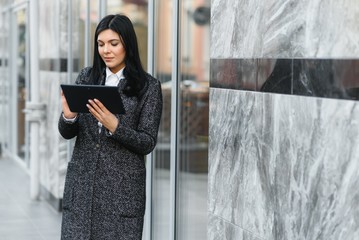 Young fashion woman using digital tablet computer outdoor Stylish female model with long brown...