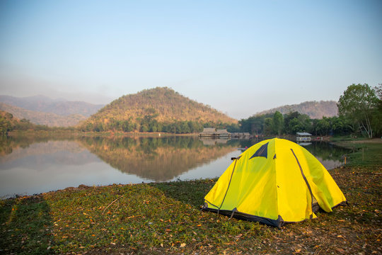Yellow tent camping beside the canal on mountain in the morning with sunrise at Suphanburi province , Thailand.