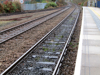 Naklejka premium The Train Track Leaving a Rural Railway Station.