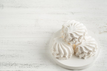 vanilla marshmallow in icing sugar on a light wooden background on a white board.