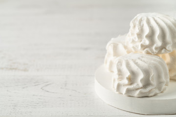 Vanilla marshmallow in icing sugar on a white board on a light wooden background