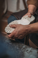 partial view of shoemaker fixing sole to boot in workshop