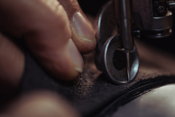 close up view of cobbler sewing genuine leather on sewing machine - obrazy, fototapety, plakaty