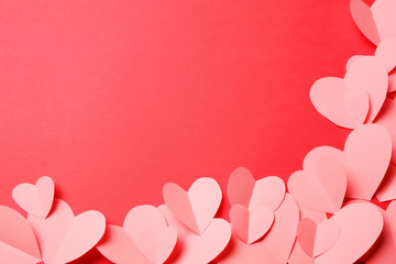 Cut out of pink paper hearts on red background