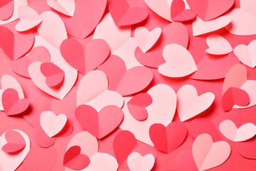 Bunch of cut out of pink and red paper hearts on red background