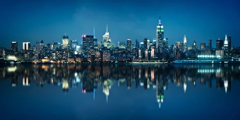 Gordijnen Panorama van de skyline van Manhattan gezien vanuit de stad Jersey tijdens het blauwe uur. New York skyline bij nacht met reflecties. © Delphotostock