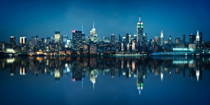 Panorama of the skyline of Manhattan viewed from Jersey city during the blue hour. New York City skyline  with the Empire State building at night with  water reflections.
