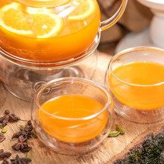 Sea Buckthorn tea candle basking in Russian restaurant. Vitaminic healthy sea buckthorn tea with cinnamon, lemon, rosemary, honey on wooden background.