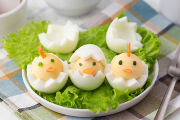 Funny healthy food for kids. Easter idea for breakfast. Boiled eggs decorated like chickens and lettuce