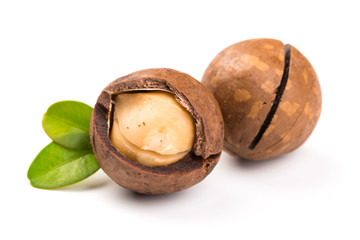 Macadamia nut with pieces and green leaves isolated on a white background