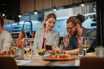 Cute caucasian fashionable couple sitting in restaurant at dinner and taking selfie.
