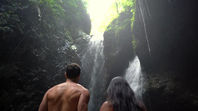 Couple looking at beautiful waterfall. The Gitgit waterfall on the island of Bali. Waterfall in the tropical forest.