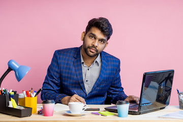 Fototapeta na wymiar Indian young businessman sitting at workplace