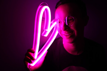 Valentine day. Hipster handsome man with neon signs. Neon sign pink heart. Party concept. Modern...