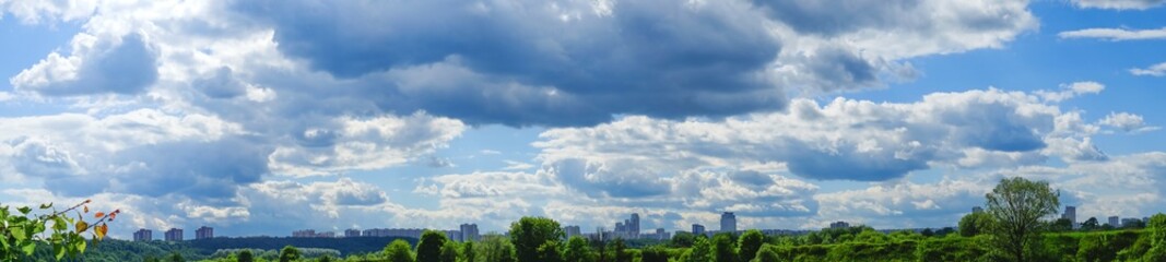 Fototapeta premium Fantastic sky over Moscow city in summertime. Panoramic view blue cloudy sky and white and rainy clouds.