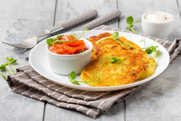 Fried potato pancakes with salmon and sour cream, fritter, roesti, golden crispy crust. Traditional...