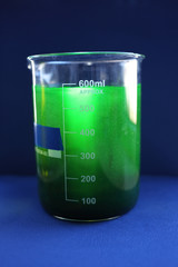 An aqueous solution of organic substance, a green fluorescent dye in a beaker through which a ray of light passes.