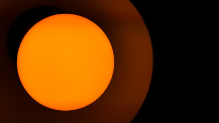 Close-up of a lamp with yellow light on a black background.