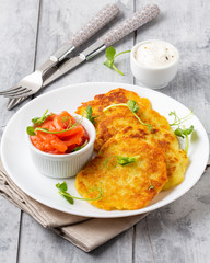 Fried potato pancakes with salmon and sour cream, fritter, roesti, golden crispy crust. Traditional delicious food