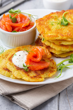 Fried potato pancakes with salmon and sour cream, fritter, roesti, golden crispy crust. Traditional delicious food