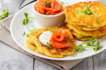 Fried potato pancakes with salmon and sour cream, fritter, roesti, golden crispy crust. Traditional delicious food