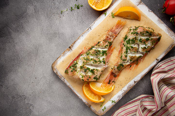 Grilled whole fish (perch, sea bass, redfish) with parsley and lemon (orange), delicious roasted food. Healthy