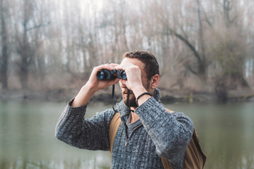 Young Man With A Backpack And Binoculars Exploring Nature