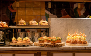 Traditional spanish snacks, appetizers or tapas called pintxos in a bar or cafe in San Sebastian, Basque country, Spain. A bar counter in a typical restaurant or tapas bar.