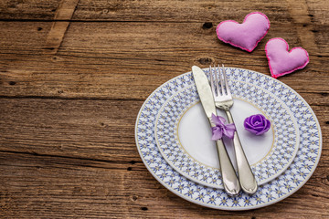 Romantic table setting on vintage wooden boards background. Valentine's day or Wedding card template. Lilac felt heart, lavender, rose flower, cutlery