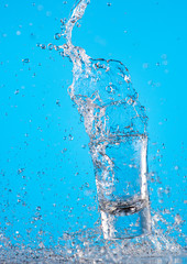 splash of pure water in a glass on a blue background