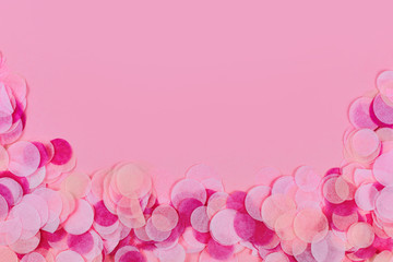 Pink party background with multicoloredpaper confetti at bottom border and copy space above