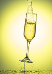 splash in a falling champagne glass on a color yellow gradient background