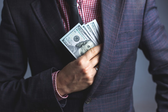 businessman in suit hides Dollars