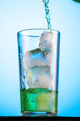 pour green carbonated tarragon lemonade in a glass with ice, flow and stream