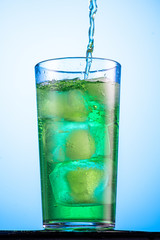 misted glass with green carbonated drink tarragon and cubes of real ice