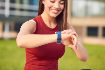 Young woman exercising / stretching in urban park and looking at the wristwatch to check time.