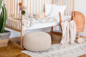 The cot is spread out. We see a crumpled pillow, plaid and blanket. The toy is also in bed. There...