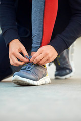 Fototapeta premium Sporty woman tying running shoes in urban park.