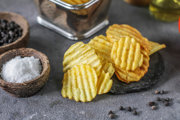Photo of potato chips on the table with ingredients around. Raw potato tomato. Salt black pepper. On a wooden table. Retro background. On dark board. Studio photography. Image