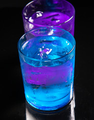 cold water with ice in a blue glass on a black background