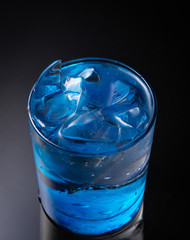 cold water with ice in a blue glass on a black background