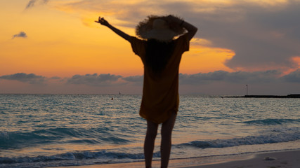 fit woman in straw hat with raised arms rejoicing