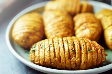 Baked Potato Hasselbeck. An accordion baked potato in a gray clay plate. Close-up. Delicious...