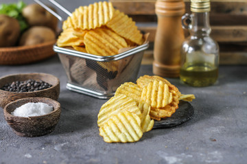 Photo of potato chips on the table with ingredients around. Raw potato tomato. Salt black pepper. On a wooden table. Retro background. On dark board. Studio photography. Image