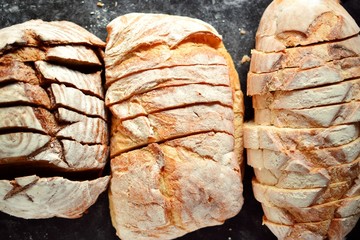 Beautiful sliced ​​bread on a dark background in flour. Bakery products. Top view, place for text. Assortment of bread.