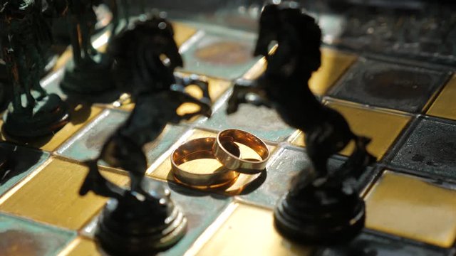 Silhouette of chess horses and wedding rings on the chessboard. Close up