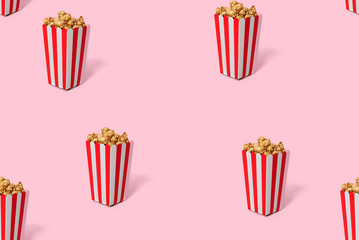 Movie Popcorn in striped red bucket isolated on pink background. Seamless pattern on a pink background