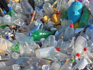 Zoom photo of pile of empty plastic bottles washed out at shore polluting sea