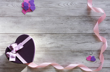 Purple and pink heart, gift box, ribbon on white wooden boards. Romantic present concept. Border, copy space, top view